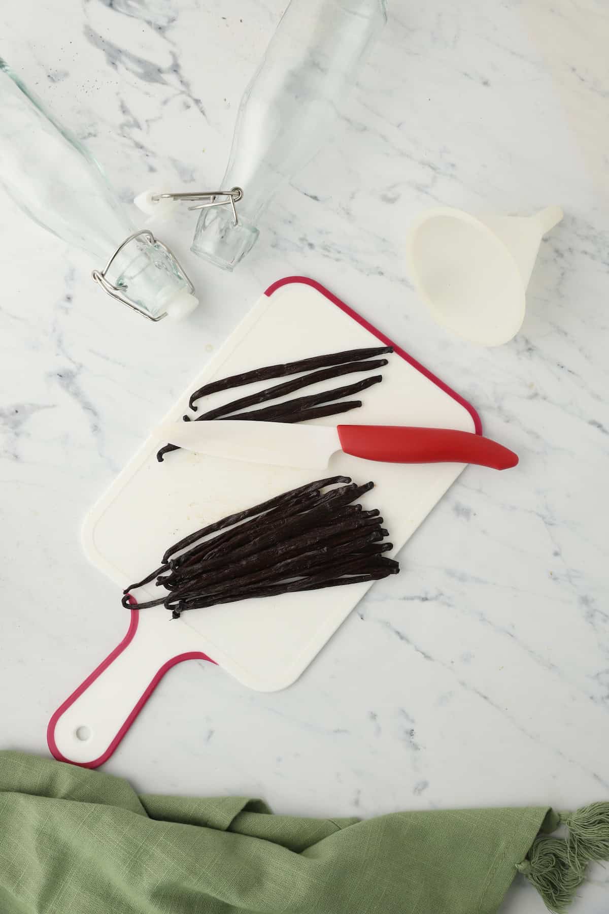 A cutting board with vanilla beans, some of which have been split open.
